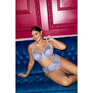 Model wearing Elomi Morgan side support banded bra and high leg brief in Blue Leopard, lounging on a blue velvet sofa